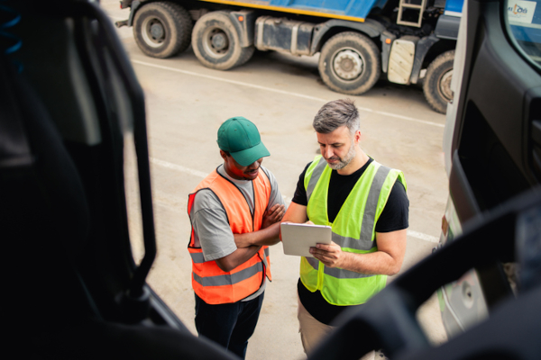 Two truck drivers going over information on a clipboard