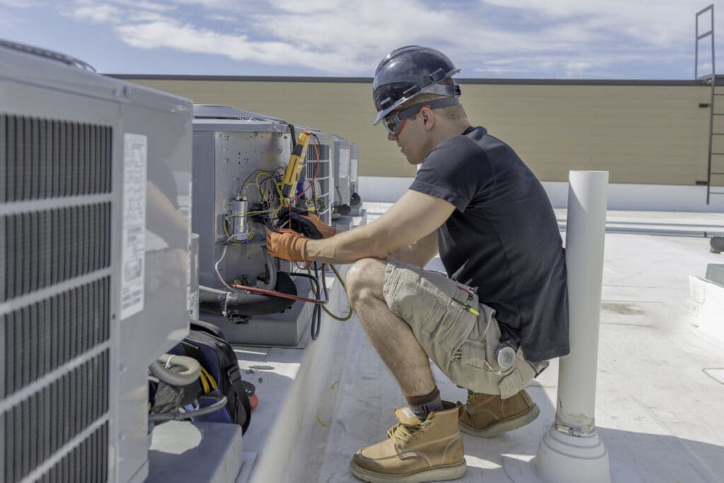 An HVAC technician working on a large rooftop unit