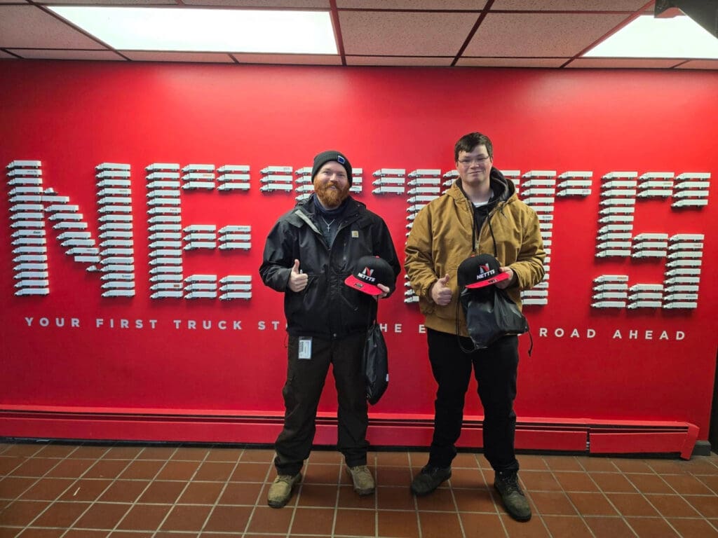 Two CDL students in front of a NETTTS sign